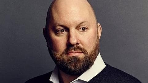 Marc Andreessen is portrayed with a thoughtful expression, wearing a dark sweater over a collared shirt against a neutral background.